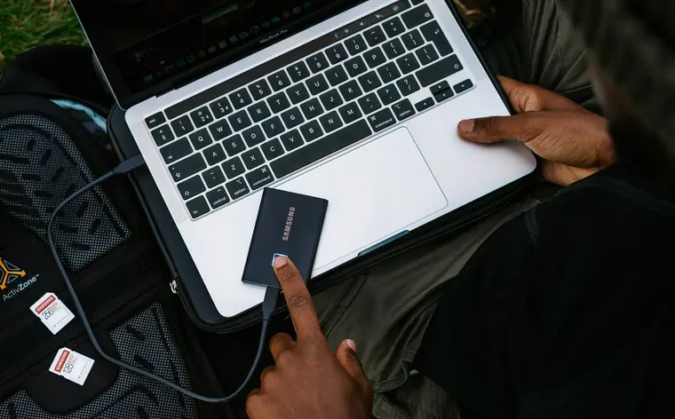 Dysk zewnętrzny podłączony do laptopa na ciemnym biurku