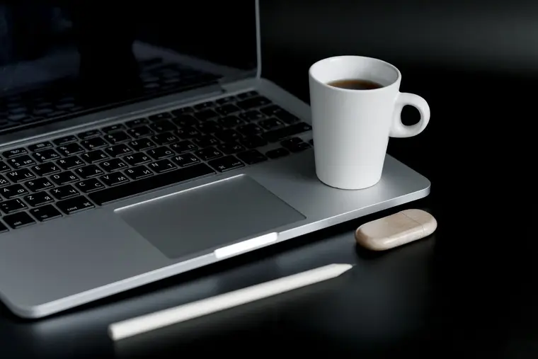 Laptop i kubek kawy na ciemnym biurku