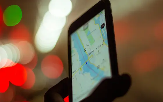 Mapa na ekranie telefonu nocą, w tle światła ulicy