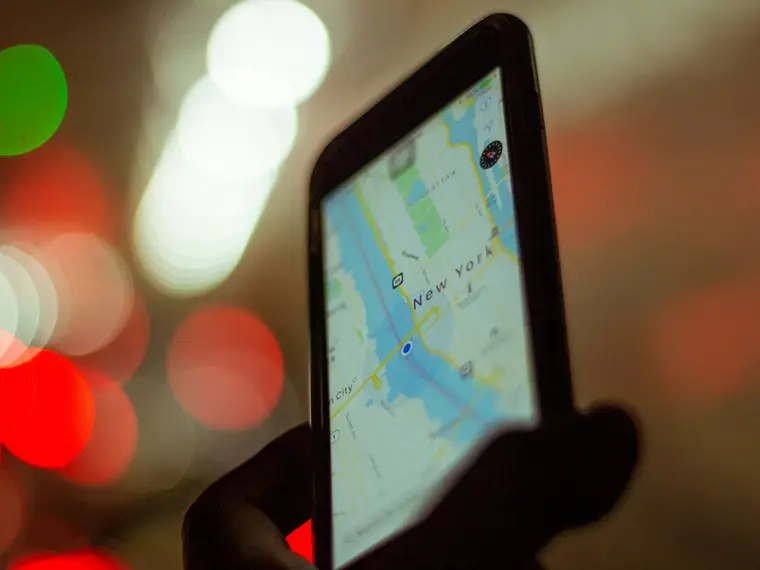 Mapa na ekranie telefonu nocą, w tle światła ulicy