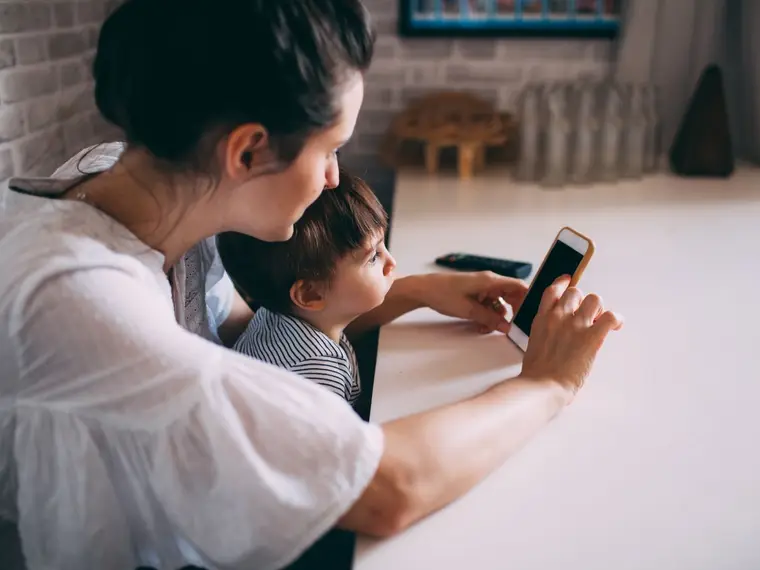 Mama pokazuje dziecku telefon przy stole