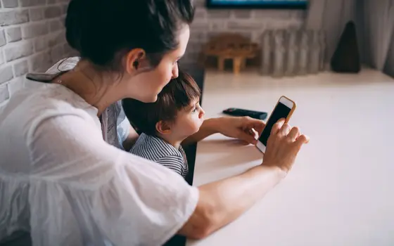 Mama pokazuje dziecku telefon przy stole
