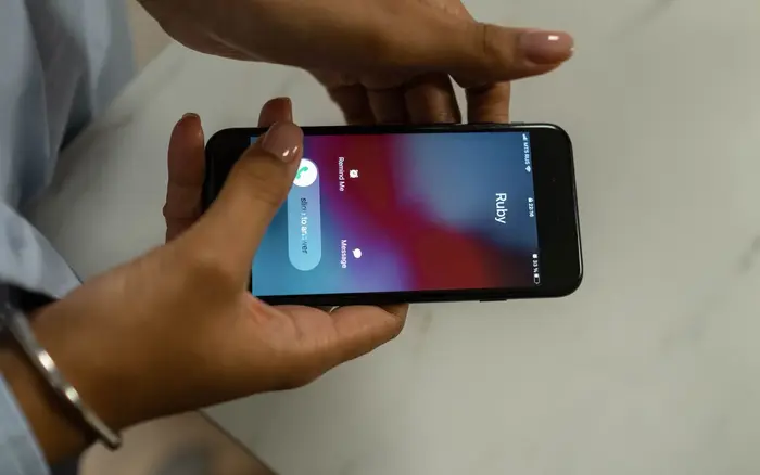 Dłonie trzymają telefon z przychodzącym połączeniem