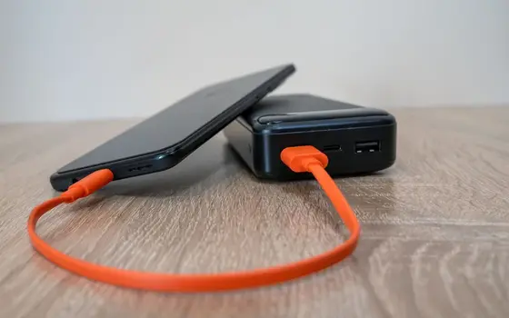 Powerbank ładujący telefon pomarańczowym kablem