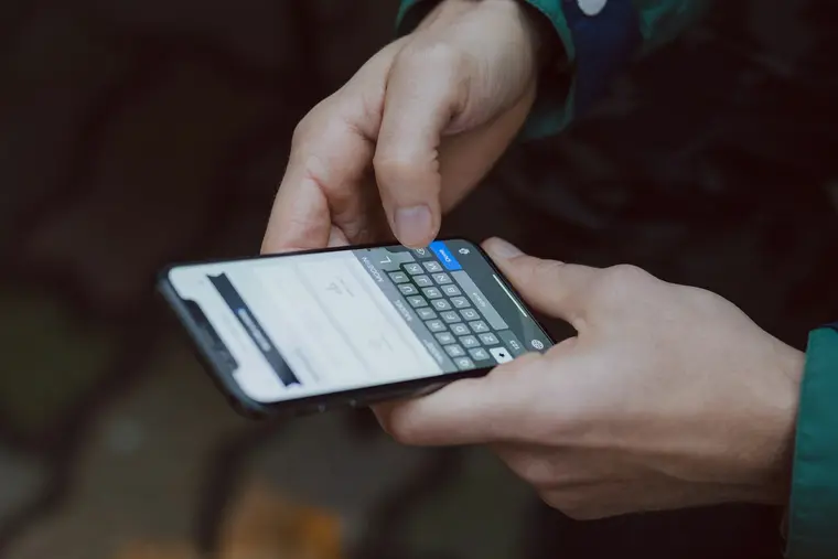 Dłonie trzymają telefon z powiadomieniami na ekranie