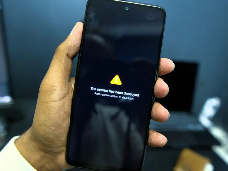 Dłoń trzyma telefon z ostrzeżeniem na ekranie w ciemności