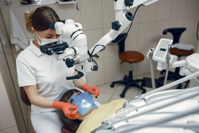 Lekarka pracuje z mikroskopem stomatologicznym przy fotelu