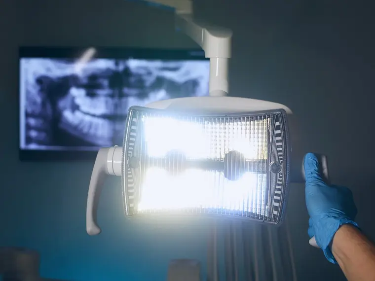 Cyfrowe zdjęcie rentgenowskie zębów na ekranie i lampa zabiegowa w ciemnym gabinecie