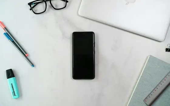 Smartfon na biurku obok długopisów i zakreślacza