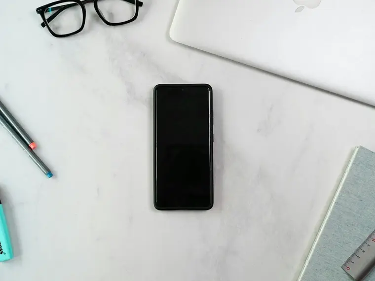 Smartfon na biurku obok długopisów i zakreślacza